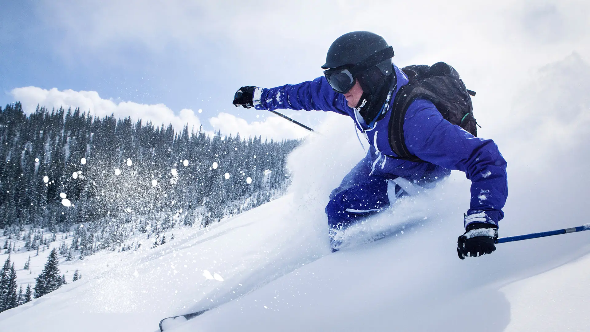 sciatore in giacca blu che curva sulla neve fresca